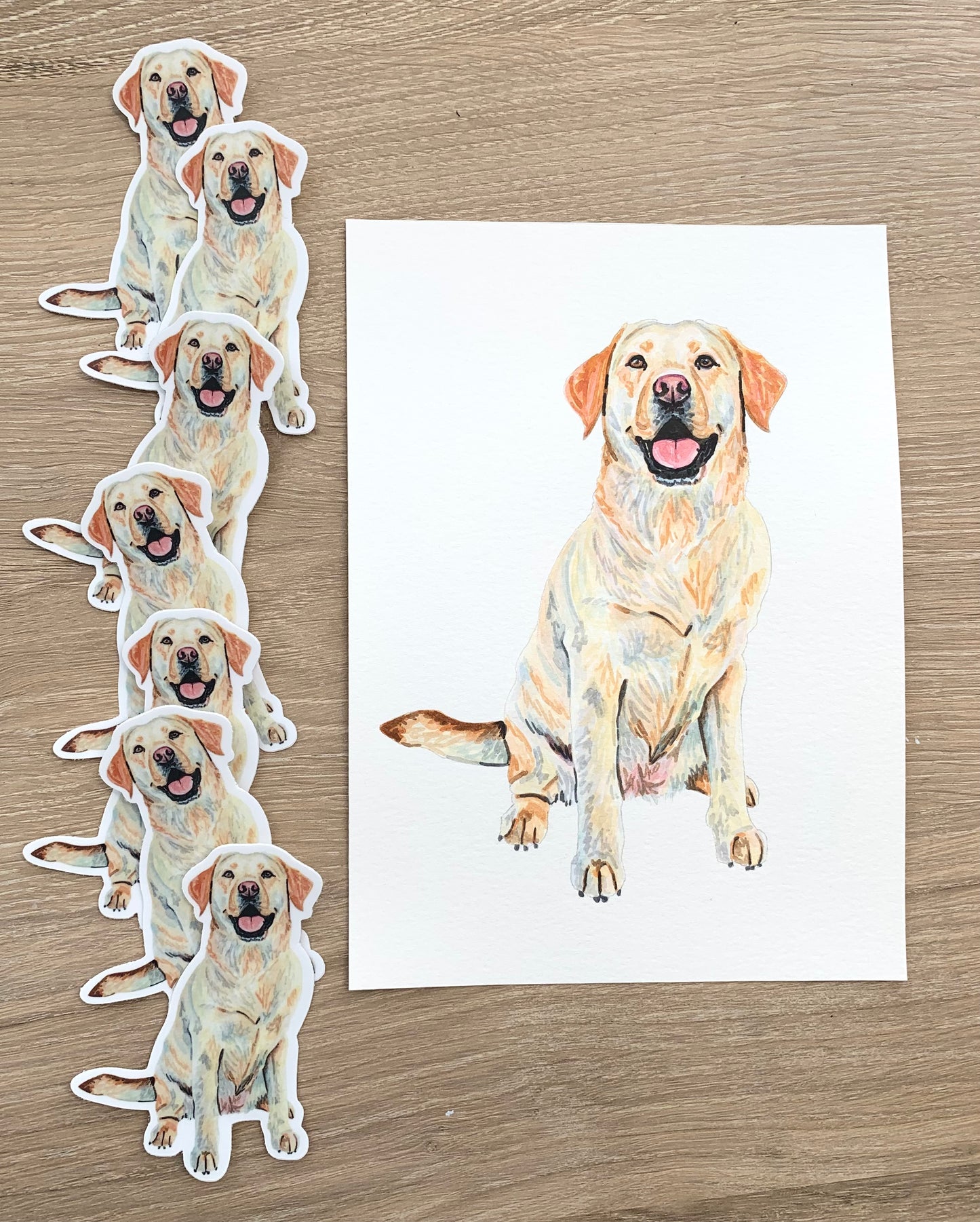 Set of yellow  Labrador Retriever stickers and a painted pet portrait on a wooden surface