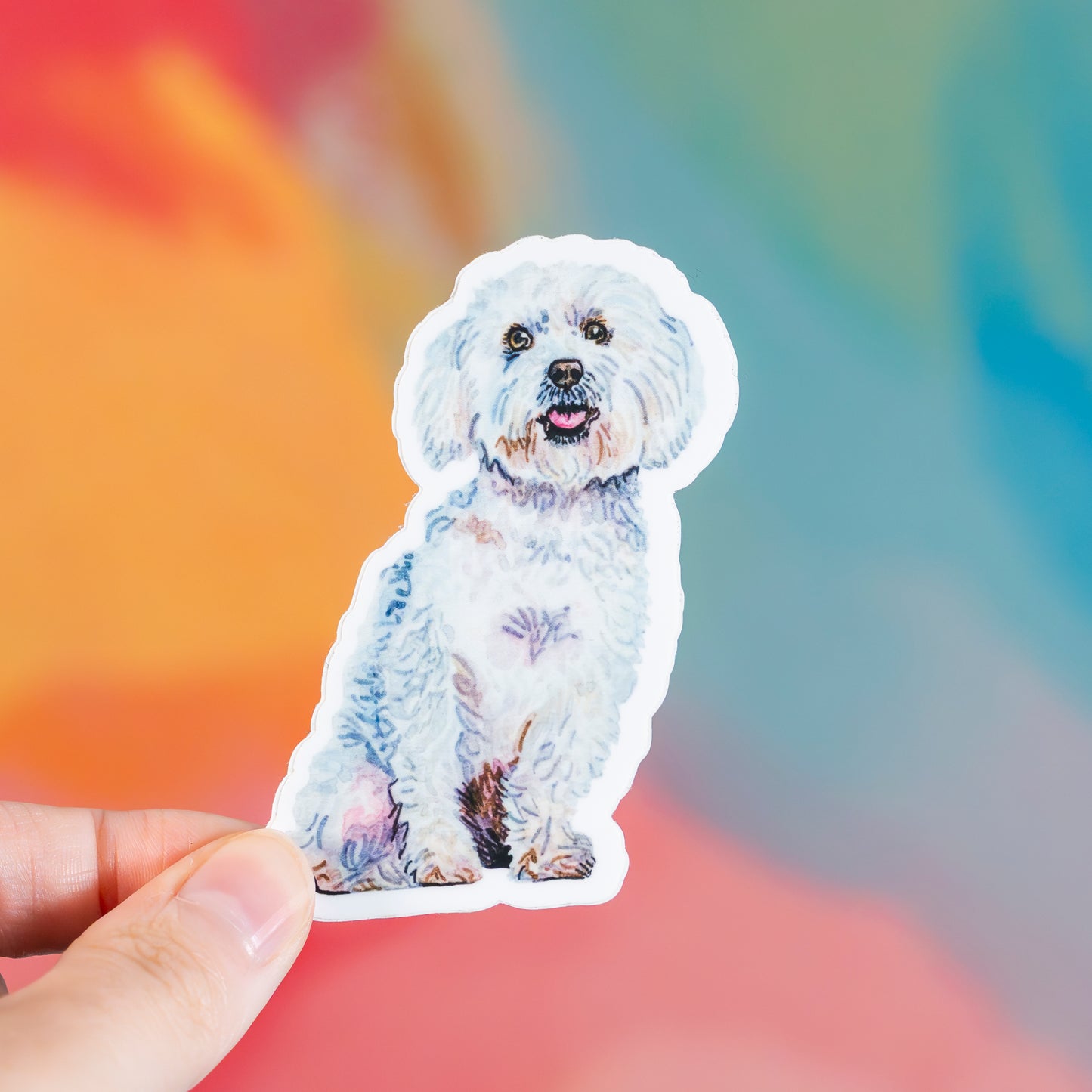 Sticker of a white dog held by a hand with a colorful blurred background