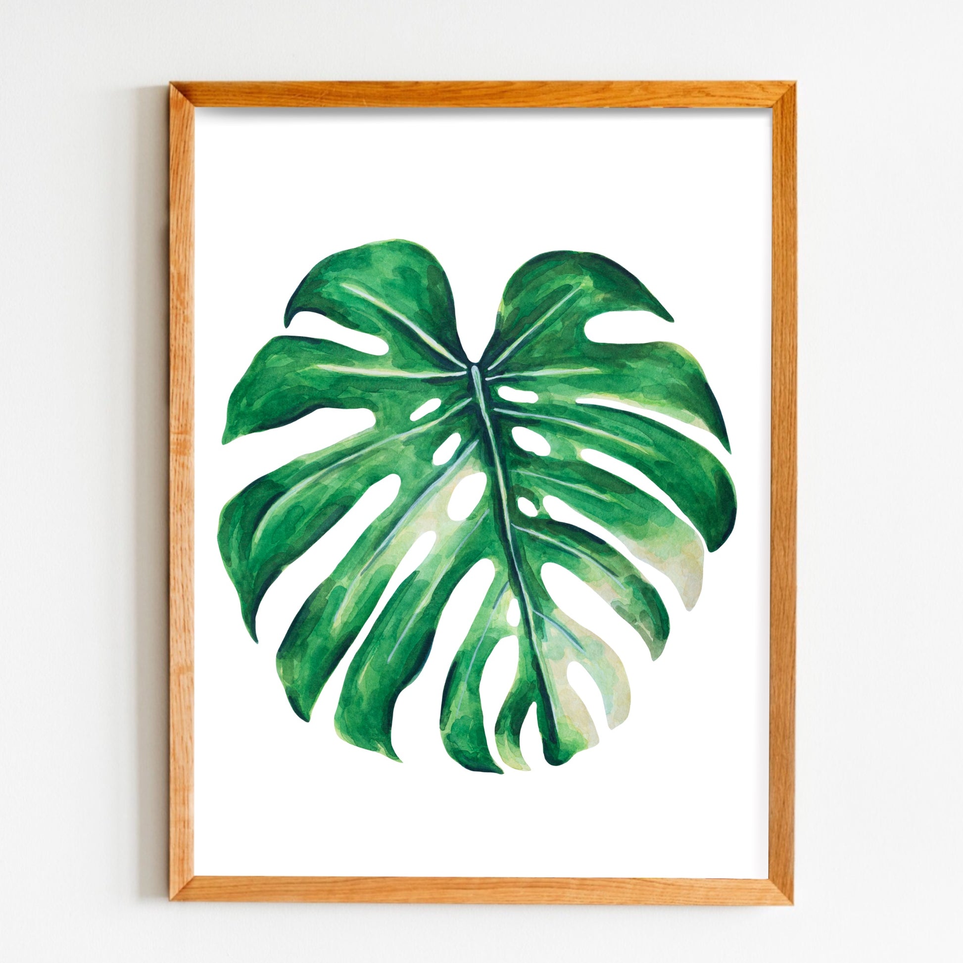 Framed artwork of a monstera leaf on a white wall