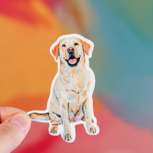 Sticker of a yellow lab dog held by a hand with a colorful blurred background